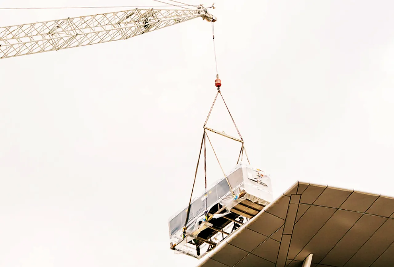 Crane lifting rooftop plant onto a commercial building