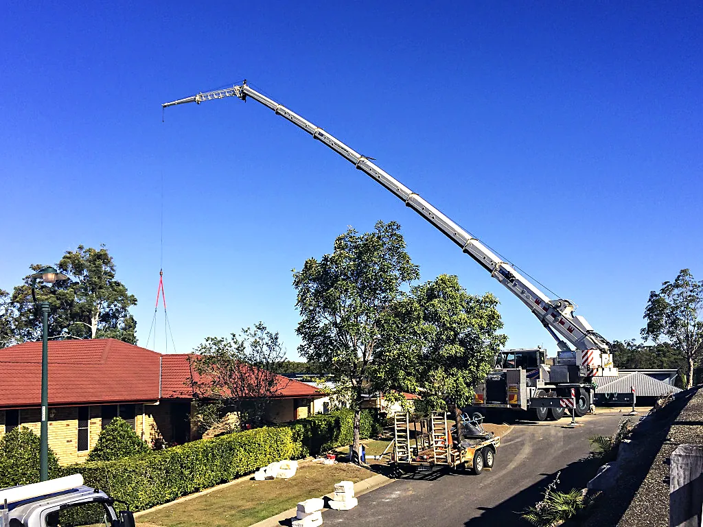 Mobile crane with extended boom on a residential street