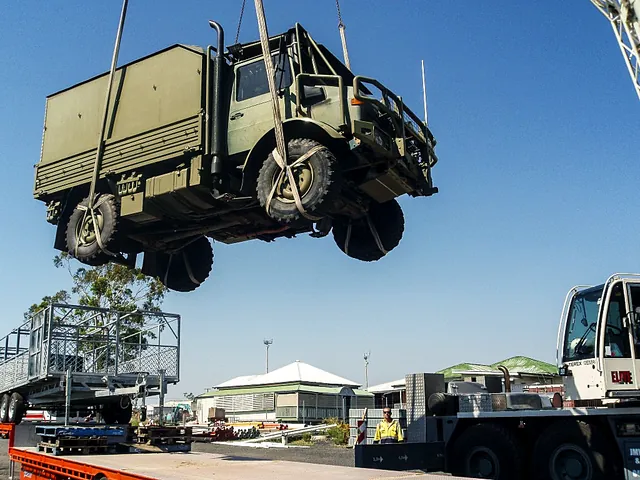 Crane lifting a truck above a trailer